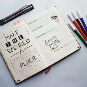 Open bullet journal with quotes and colorful markers for planning and creativity.