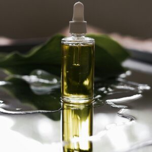 Close-up of a luxury skincare oil bottle with a dropper, reflected on a wet surface.